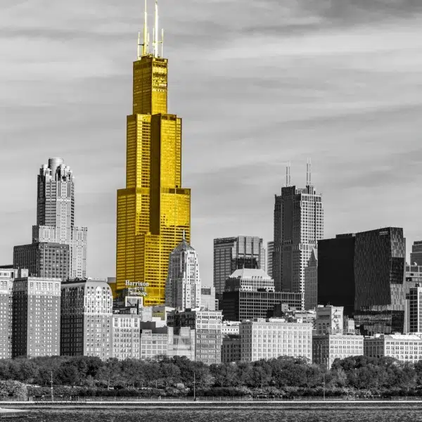 Black and white photo of a city. Skyscraper colored yellow.