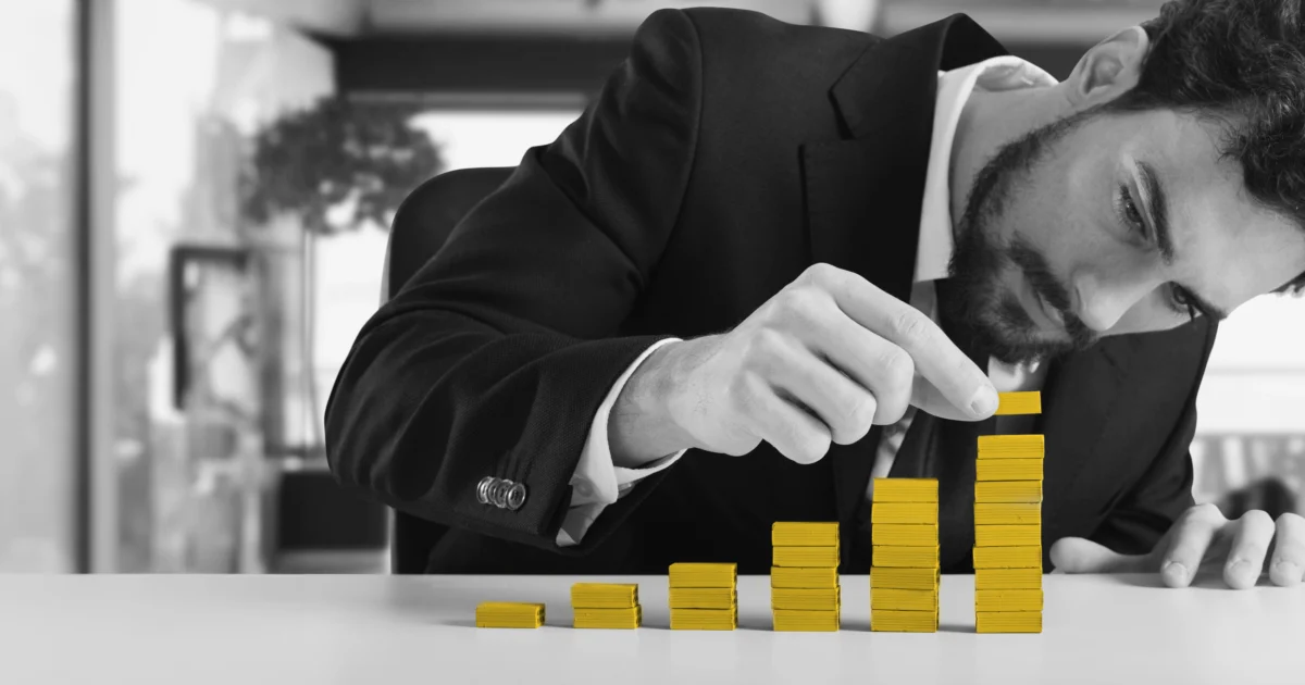 Black and white photo of a main in a suit stacking small boxes. Small boxes are colored yellow.