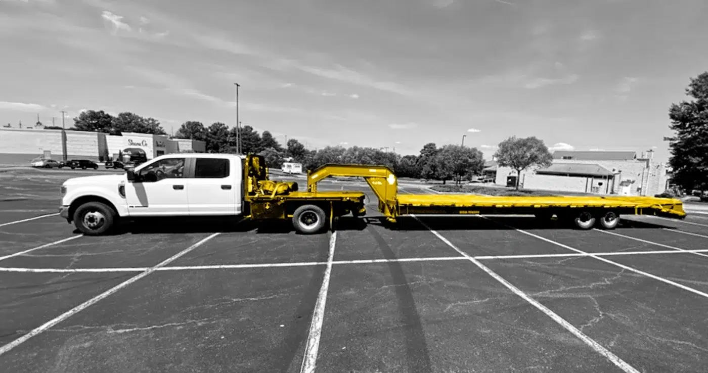 Black and white photo of a Dodge Ram with a flatbed hot shot attachment. Attachement colored yellow.