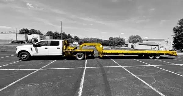 Black and white photo of a Dodge Ram with a flatbed hot shot attachment. Attachment colored yellow.