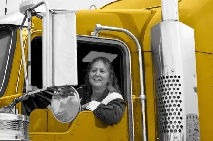 Woman driver sitting in the cabin of her yellow truck