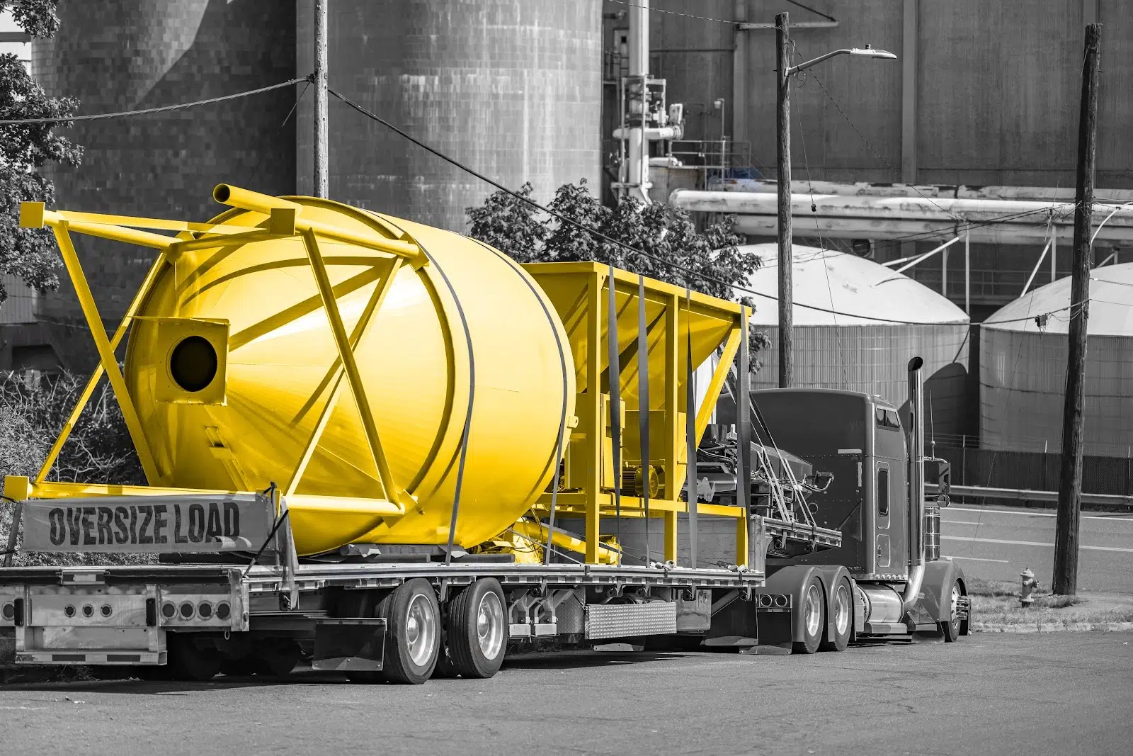 Black and white photo of a truck carrying oversized load. Load colored yellow.