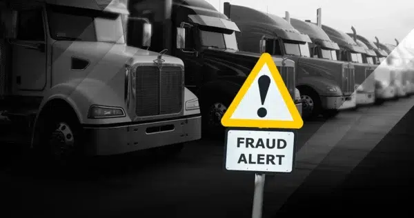 Black and white photo of trucks and the big yellow sign saying Fraud Alert.